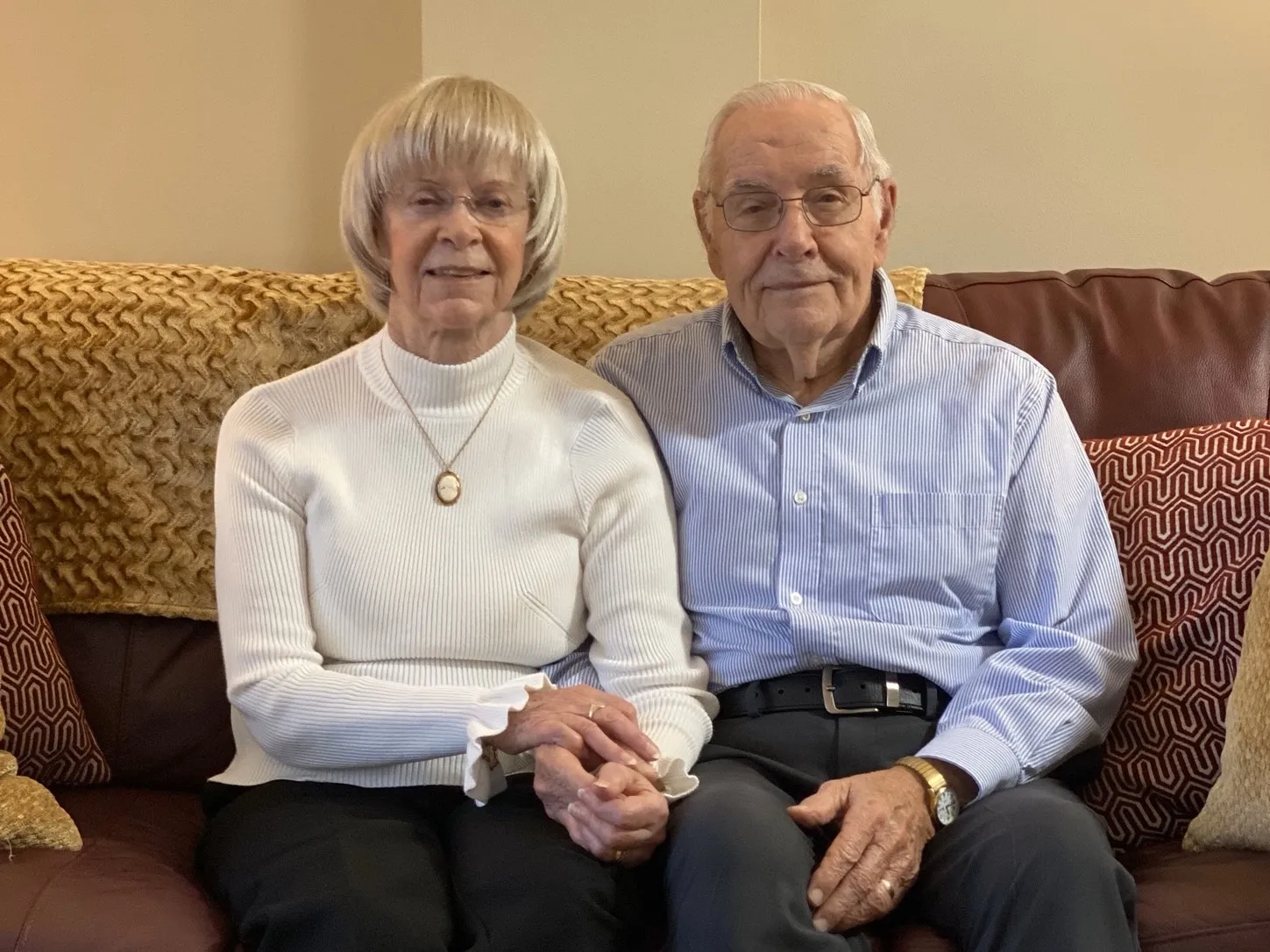Betty Collins and Bill O'Byrne sitting on the couch holding hands